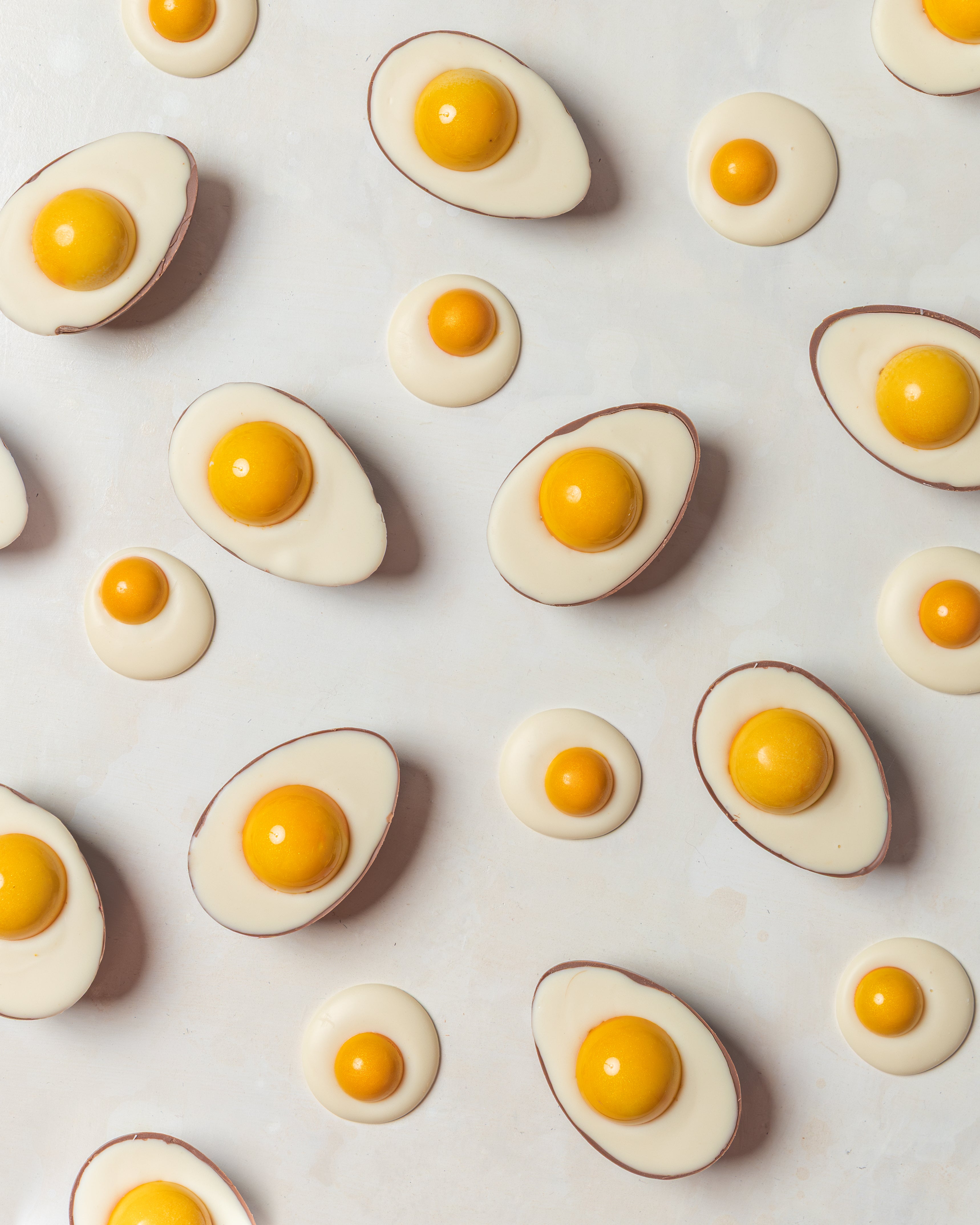 Egg-shaped Cocoa Nib chocolates arranged on a pale surface.
