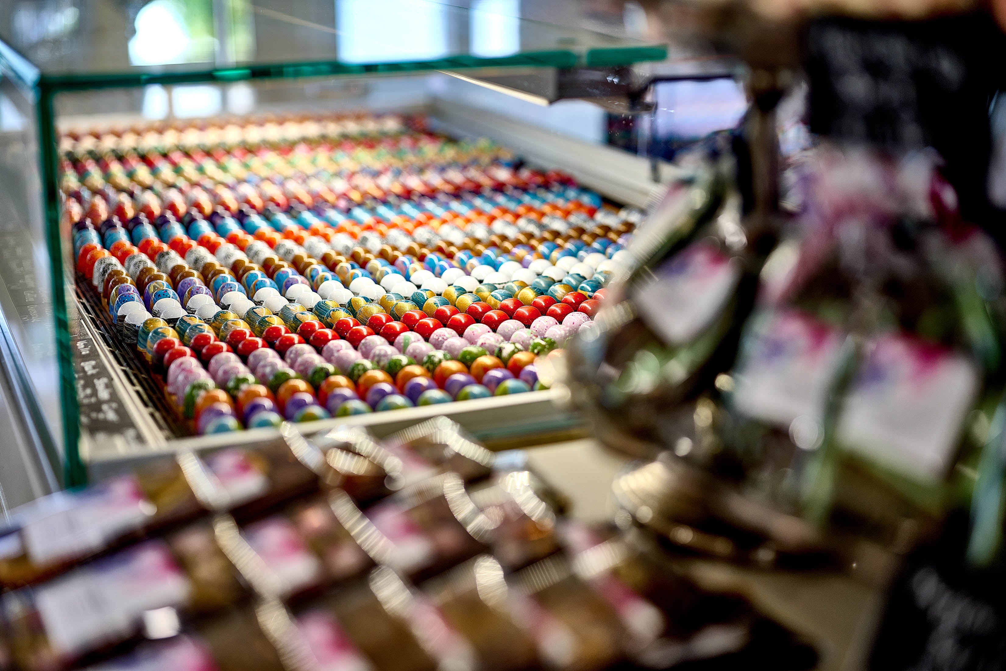 Colourful Cocoa Nib bonbons in a glass shop display.