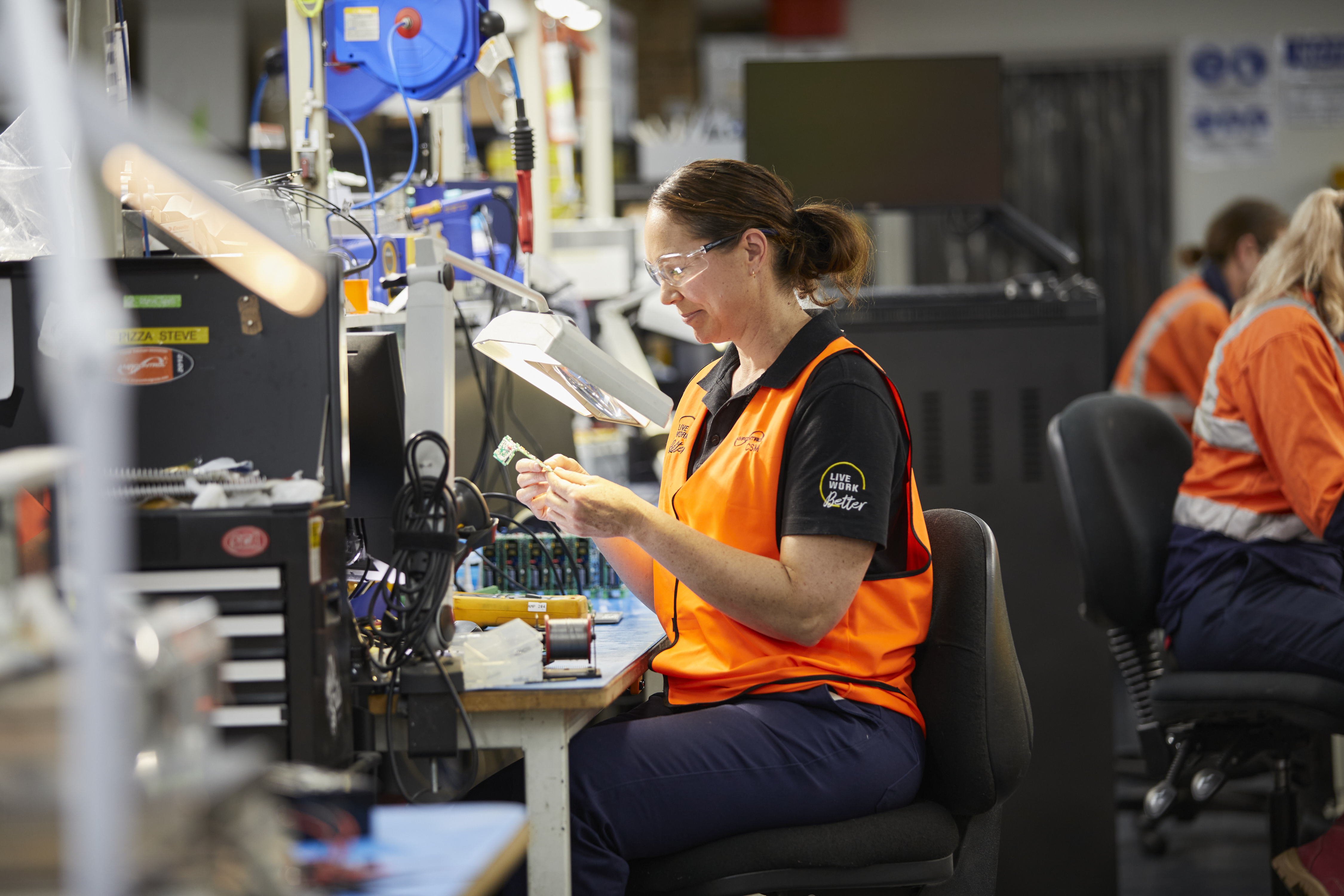 Ampcontrol employee inspecting a circuit board at a workbench.