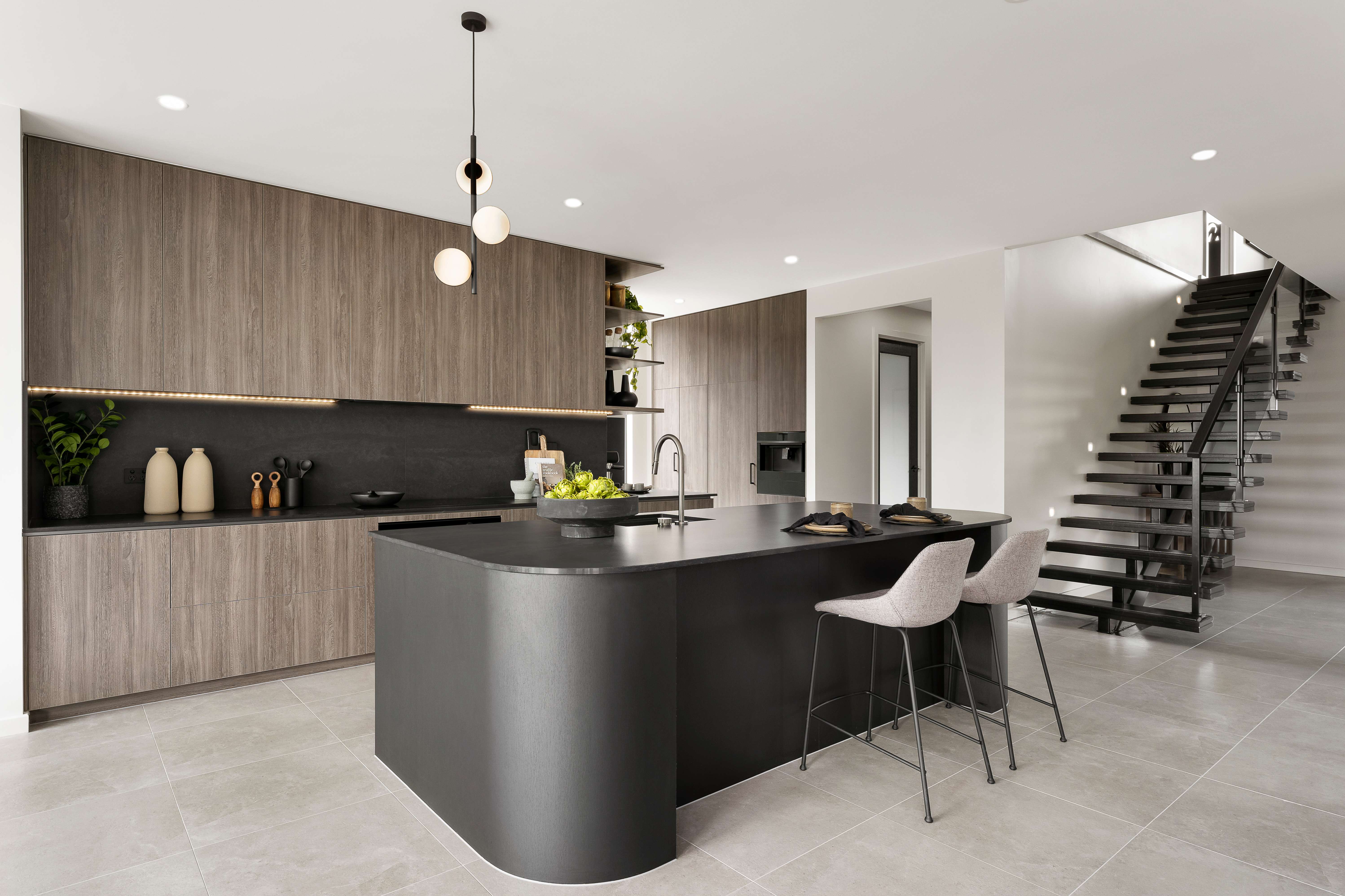 McDonald Jones kitchen with timber cabinetry, a dark island and an open staircase.